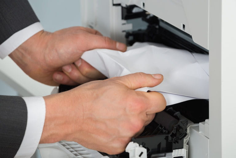 Close-up Of Businessman Hand Removing Paper Stuck In Printer At Office