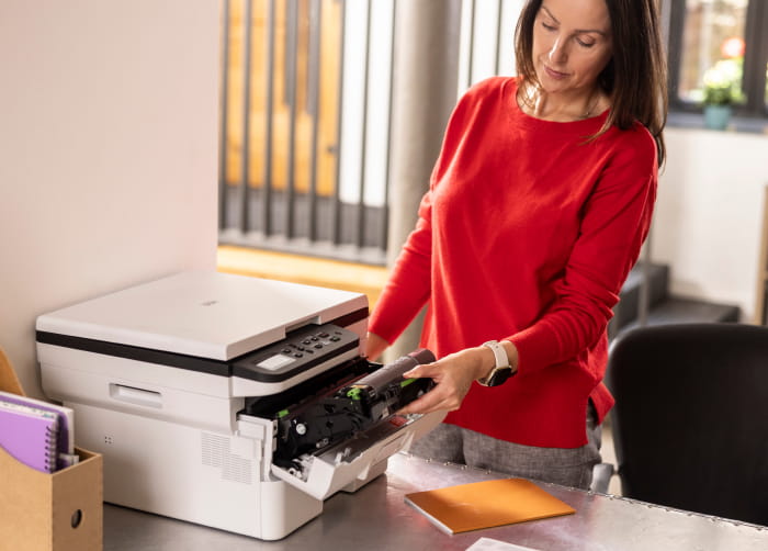 A woman operates a printer, producing documents in an office setting, showcasing her focus and efficiency in the task. Brother Gulf, Middle East & Africa